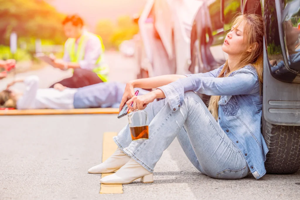 A drunk woman sitting by her car.
