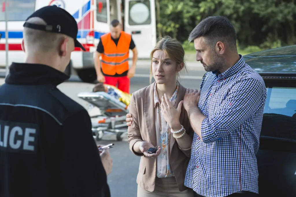 Police officer speaking with car accident victims.