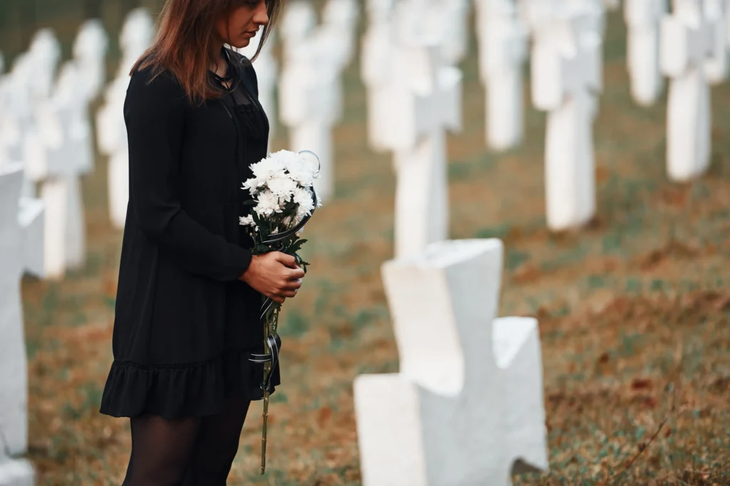 A woman standing at a grave mourning.